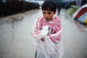 A migrant boy walks under the rain on March 10, 2016, at the makeshift camp of the Greek-Macedonian border, near the Greek village of Idomeni, where thousands of refugees and migrants are stranded by the Balkan border blockade.  The main migrant trail from Greece to northern Europe was blocked March 9 after western Balkan nations slammed shut their borders, hiking pressure for an EU-Turkey deal and exacerbating a dire situation on the Macedonian border. More than 14,000 mainly Syrian and Iraqi refugees are camping out by the northern Idomeni border crossing with Macedonia -- many of them for weeks -- at a muddy, unhygienic camp operated by beleaguered aid groups.  / AFP / DIMITAR DILKOFF