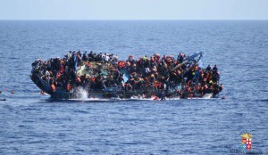 People jump out of a boat right before it overturns off the Libyan coast, Wednesday, May 25, 2016. The Italian navy says it has recovered 7 bodies from the overturned migrant ship off the coast of Libya. Another 500 migrants who on board were rescued safely. (Marina Militare via AP Photo)