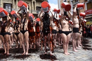 Pro-animal rights activists pour fake blood on themselves to protest against bullfighting and bull-running during a demonstration called by the People for the Ethical Treatment of Animals (PETA) and Anima Naturalis pro-animal groups on the eve of the San Fermin festivities in the Northern Spanish city of Pamplona on July 5, 2016.  The San Fermin festival is a symbol of Spanish culture that attracts thousands of tourist to watch the bull runs despite heavy condemnation from animal rights groups. / AFP PHOTO / ANDER GILLENEA