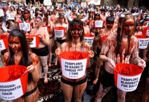 Activists covered in fake blood protest against bullfighting and bull-running during a demonstration called by the People for the Ethical Treatment of Animals (PETA) and Anima Naturalis pro-animal groups on the eve of the San Fermin festivities in the Northern Spanish city of Pamplona on July 5, 2016.  The San Fermin festival is a symbol of Spanish culture that attracts thousands of tourist to watch the bull runs despite heavy condemnation from animal rights groups. / AFP PHOTO / ANDER GILLENEA