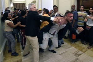 An opposition deputy struggles while pro-government supporters force their way to the National Assembly during an extraoridinary session called by opposition leaders, in Caracas on October 23, 2016. The opposition Democratic Unity Movement (MUD) called a Parliamentary session to debate putting President Nicolas Maduro on trial to "restore democracy" in an emergency session that descended into chaos as supporters of the leftist leader briefly seized the chamber. / AFP PHOTO / JUAN BARRETO