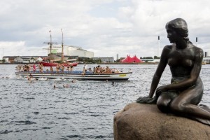 100 girls jump in the water behind Copenhagen's landmark "Little Mermaid" at Langelinie in Copenhagen, on August 23, 2013 as the statue celebrates her 100th birthday. Perched in the water just off the star-shaped Kastellet fortress near the city's harbour, the small bronze skinned sculpture of H.C. Andersen's melancholic fairytale has become a Danish icon on par with Carlsberg, the brewery whose owner once financed her.  AFP PHOTO / Scanpix Denmark/ NIKOLAI LINARES   DENMARK OUT / AFP PHOTO / SCANPIX DENMARK / Nikolai Linares