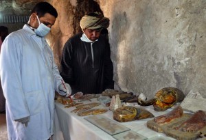 Members of an Egyptian archaeological team stand near artifacts discovered in a 3,500-year-old tomb in the Draa Abul Nagaa necropolis, near the southern city of Luxor, on April 18, 2017. Egyptian archaeologists have discovered six mummies, colourful wooden coffins and more than 1,000 funerary statues in the 3,500-year-old tomb, the antiquities ministry said. / AFP PHOTO / STRINGER