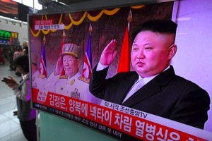 People walk past a television screen broadcasting live footage of a parade to mark the 105th anniversary of the birth of North Korea's founder Kim Il-Sung and showing North Korean leader Kim Jong-Un (R), at a railway station in Seoul on April 15, 2017. North Korean leader Kim Jong-Un on April 15 saluted as ranks of goose-stepping soldiers followed by tanks and other military hardware paraded in Pyongyang for a show of strength with tensions mounting over his nuclear ambitions. / AFP PHOTO / JUNG Yeon-Je