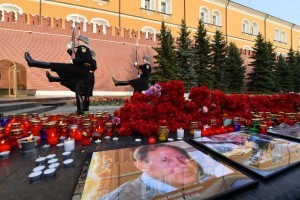 Flowers and candles left in tribute to the victims of April 3 blast in the Saint Petersburg metro are seen by a memorial stone reading Leningrad by the Kremlin wall as honour guard soldiers march during the changing of the guards ceremony in central Moscow on April 6, 2017. / AFP PHOTO / Natalia KOLESNIKOVA