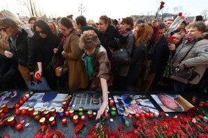 People place flowers and candles in honour of the victims of April 3 blast in the Saint Petersburg metro by a memorial stone reading Leningrad by the Kremlin wall during a commemorative event in central Moscow on April 6, 2017. / AFP PHOTO / Natalia KOLESNIKOVA