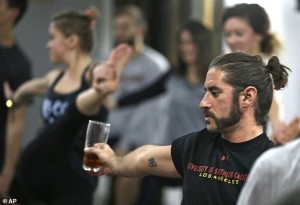 In this Thursday, Dec. 3, 2015 photo, Reed Patterson practices yoga while holding onto his beer at the Platform Beer Co., in Cleveland. Craft breweries are partnering up with yoga studios around the country as more breweries are hosting classes to attract a new crowd to the bars and yoga studios are using the beer to get more men to try yoga. (AP Photo/Tony Dejak)