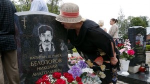 epa04350458 A relative of 3rd rank Captain Nikolai Belosorov kisses his tombstone at the Serafimovskoye cemetery during the memorial ceremony on the 14th anniversary of the Kursk submarine tragedy, in St. Petersburg, Russia, 12 August 2014. Nuclear submarine 'Kursk' sank in Barents Sea taking the lives of 118 sailors on 12 August 2000.  EPA/ANATOLY MALTSEV