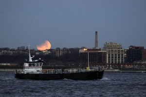 epa06488236 A tug boat is seen sailing past a Super Blue Blood Moon as its photographed over Jersey City, New Jersey, USA, 31 January 2018. The moon is a supermoon, blue moon and total lunar eclipse that NASA has dubbed a 'Super Blue Blood Moon'. This is the last one in a series of three consecutive 'Supermoons', dubbed the 'Supermoon Trilogy'.  The previous 'Supermoons' appeared on 03 December 2017 and on 01 January 2018. A 'Supermoon' commonly is described as a full moon at its closest distance to the earth with the moon appearing larger and brighter than usual.  EPA/JASON SZENES