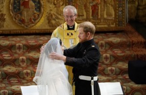 Britain's Prince Harry, Duke of Sussex (R) removes the veil of US actress Meghan Markle (L) as they stand at the altar together before Archbishop of Canterbury Justin Welby (C) in St George's Chapel, Windsor Castle, in Windsor, on May 19, 2018 during their wedding ceremony. / AFP PHOTO / POOL / Owen Humphreys